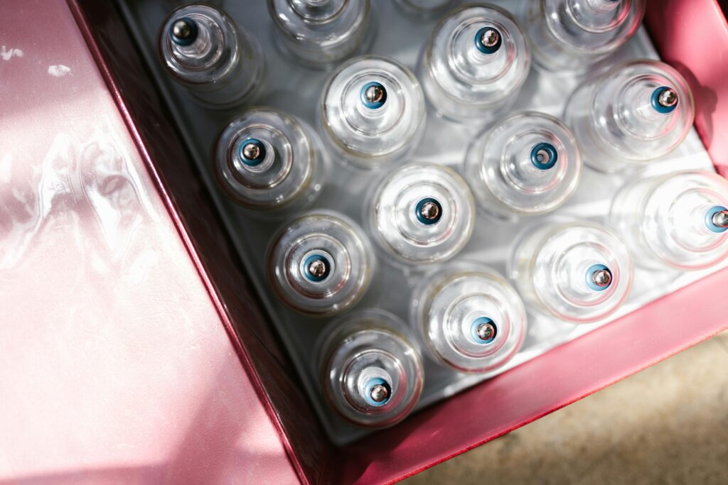 Aerial view of glass cupping therapy sets neatly arranged in a red box under sunlight.